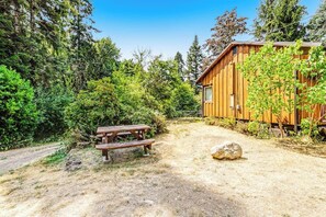 Eine Holzhütte mit einem Picknicktisch in einem bewaldeten Gebiet.