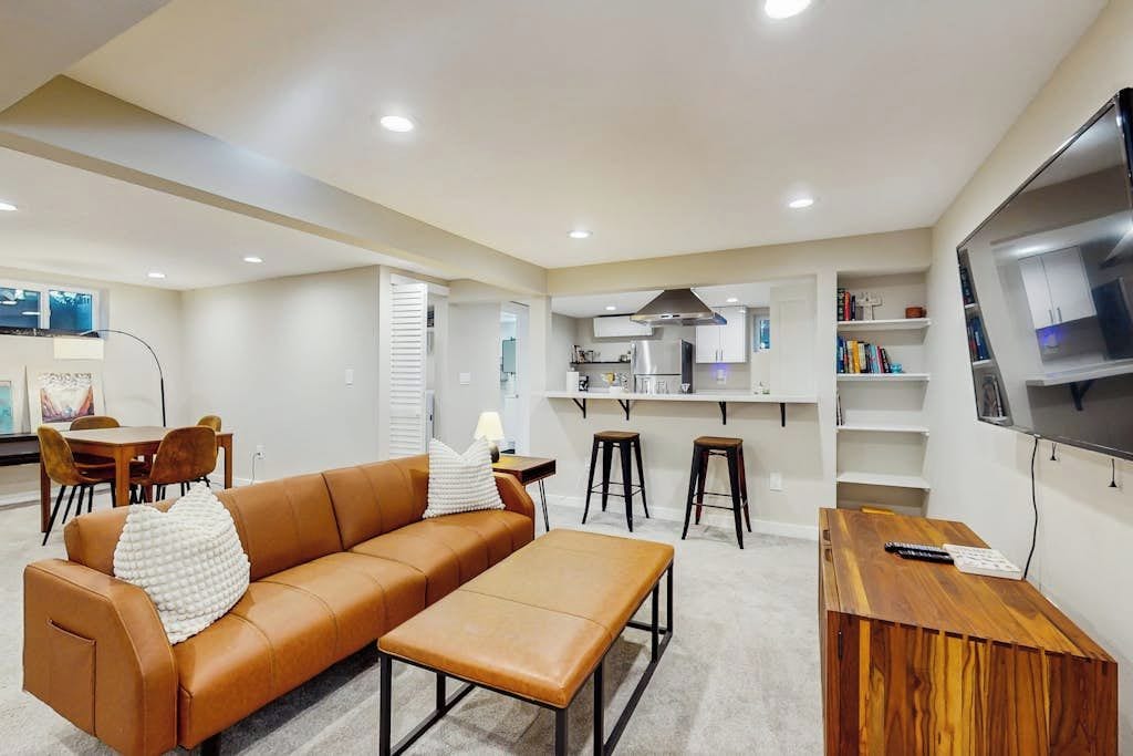 Una sala moderna con un sofá, una mesa de centro, un televisor y una cocina al fondo.