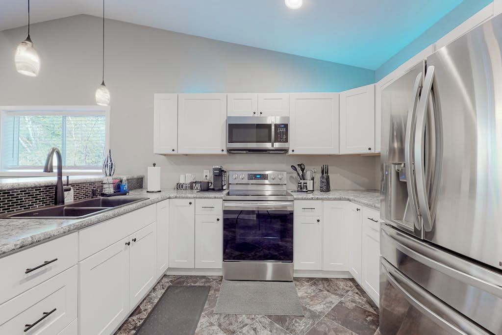 A modern kitchen with white cabinets, stainless steel appliances, and a granite countertop.