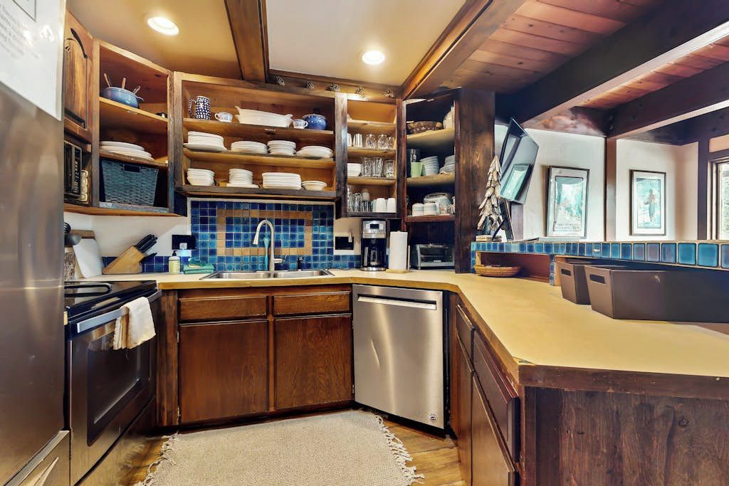 A kitchen with wooden cabinets, a dishwasher, and a tiled backsplash.