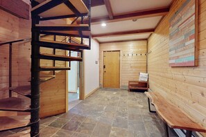 A wooden interior with a spiral staircase, a wooden door, and a wall with a list of amenities. - 3BR ski-in and out A-frame duplex with deck & firepit (Snoqualmie Pass)