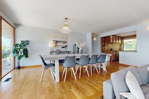 Een moderne eetruimte met een houten tafel en stoelen, een kroonluchter en uitzicht op de keuken.