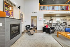 A modern living room with a fireplace, seating area, and a kitchen in the background. - 2BR oceanfront house with beach access (Westport)