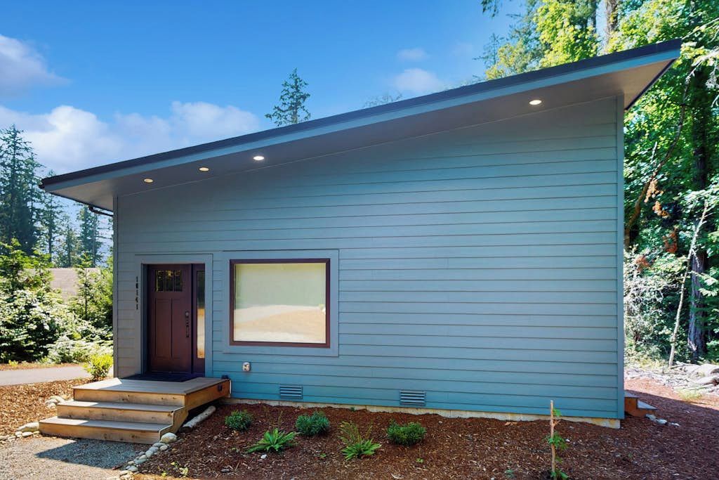 Une maison moderne de plain-pied, dotée d’un porche à l’avant, d’une porte et d’une fenêtre.