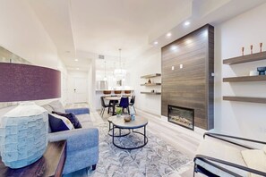 Ein modernes Wohnzimmer mit Kamin, Essbereich und einer Sitzecke mit Sofa und Sesseln.