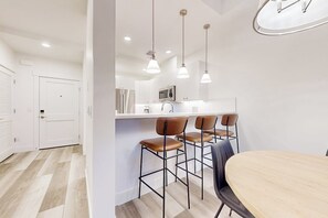 Une cuisine moderne avec des meubles blancs, un îlot central et des luminaires suspendus.