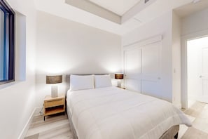 Ein Schlafzimmer mit einem großen Bett, zwei Nachttischen mit Lampen, einem Kleiderschrank und einem Fenster.