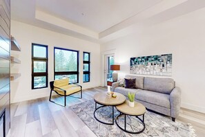 Un salon moderne avec un canapé, deux fauteuils, une table basse et une grande fenêtre.