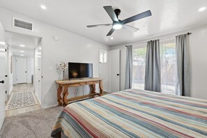 A bedroom with a bed, a TV on a wooden stand, a ceiling fan, and a window with curtains. - *New* Close to Uof A & Downtown~Sleeps7~Casa Elida (Tucson)