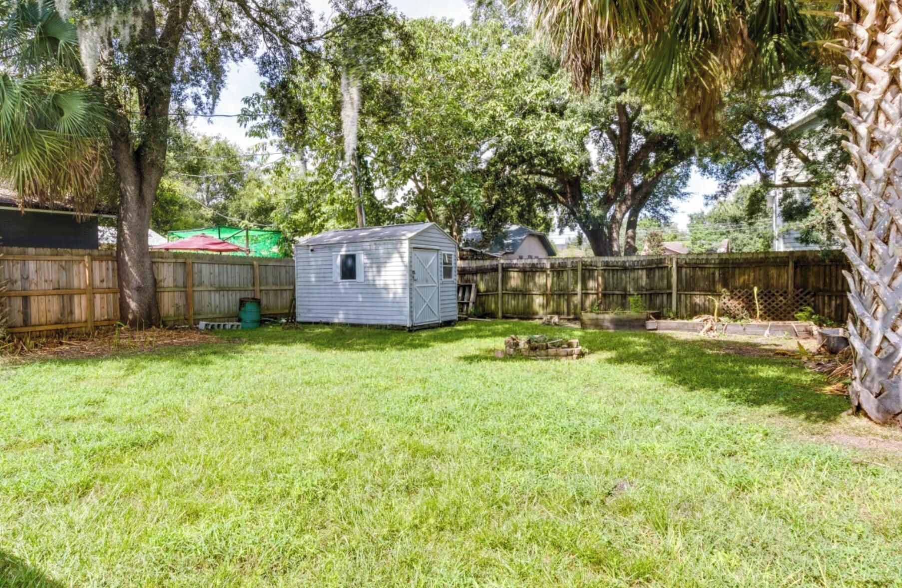 A backyard with a small shed, a wooden fence, and a grassy lawn.