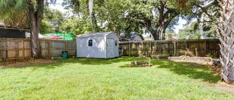 A backyard with a small shed, a wooden fence, and a grassy lawn.