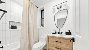 A modern bathroom with a bathtub, toilet, and vanity.