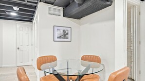 A conference room with a glass table and leather chairs, white walls, and a framed picture on the wall.