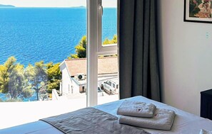 A hotel room with a bed, a window with a view of the sea, and a painting on the wall. - Amazing home in Blato with private swimming pool, can be inside or outside (Blato)