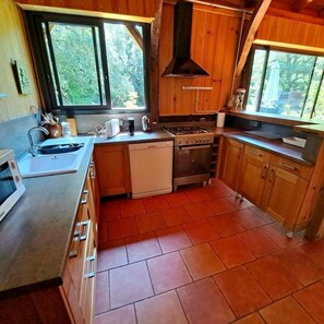Eine kleine Küche mit Holzausstattung, einem Spülbecken, einem Herd und einem Geschirrspüler.