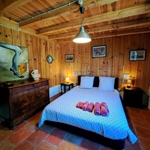 Ein Zimmer mit Holzwänden, einem Bett, einer Kommode und einem Gemälde.