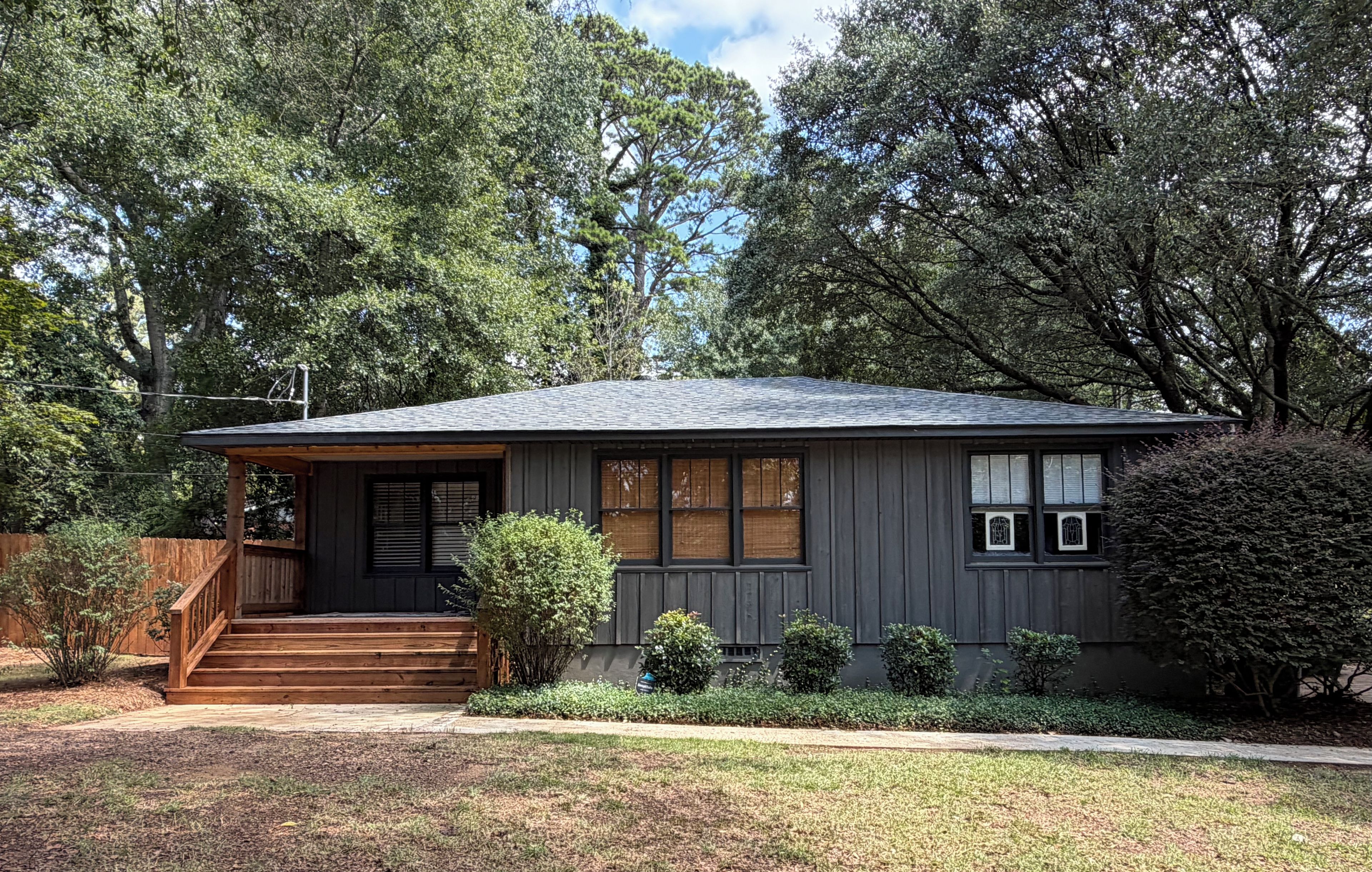 A single-story house with a front porch, a small front yard, and a wooden fence.