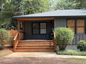 A two-story house with a wooden porch, a front door with a window, and a small garden area. - 2 miles to Toomer's Corner - FREE PARKING 1 mile from Campus - AUBURN RETREAT (Auburn)