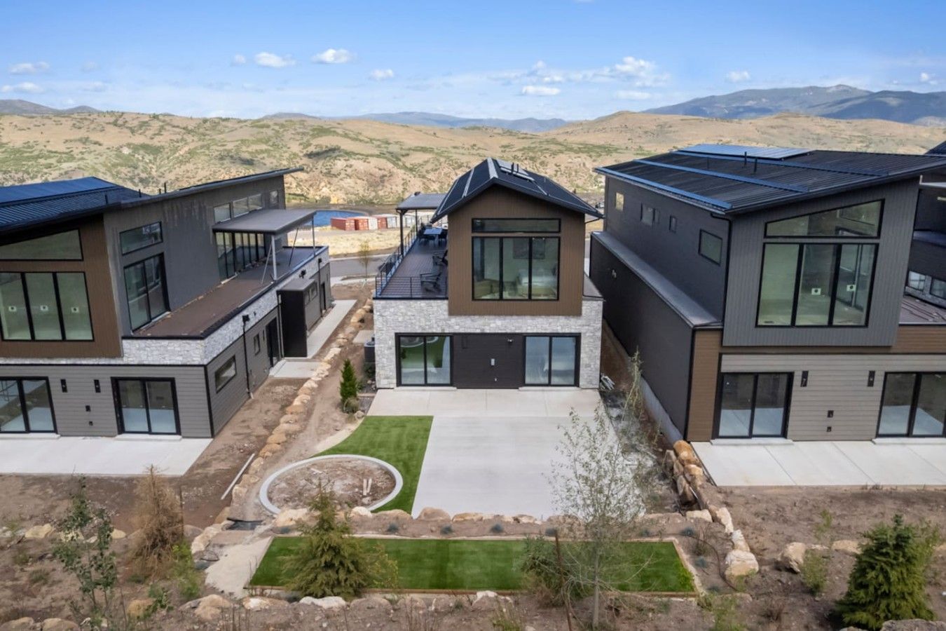 A modern residential complex with multiple two-story houses, a central courtyard, and a view of distant mountains.