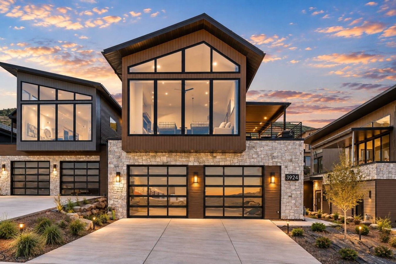 A modern two-story house with a stone facade, large windows, and a garage.
