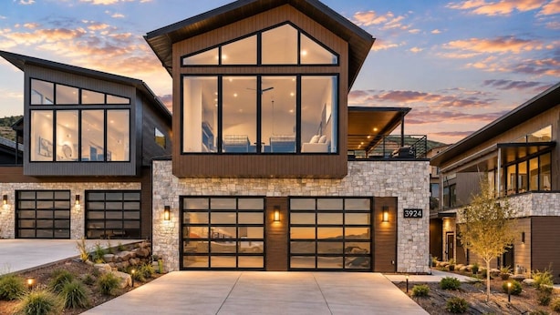 A modern two-story house with a stone facade, large windows, and a garage. - Ski & Lake Retreat | Golf Sim + Sauna + Firepit (Daniel)