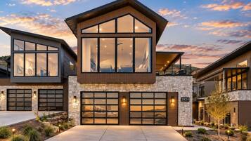 A modern two-story house with a stone facade, large windows, and a garage.