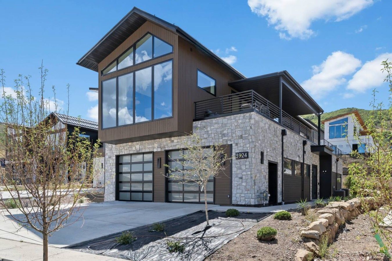 A modern two-story house with a stone facade, large windows, and a flat roof.