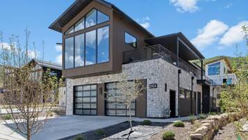 A modern two-story house with a stone facade, large windows, and a flat roof.