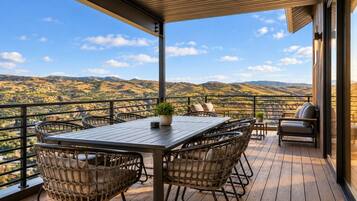 A wooden deck with a table and chairs, overlooking a mountainous landscape.