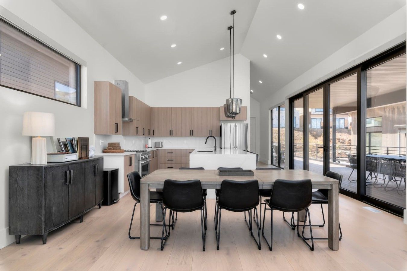 A modern kitchen with a central island, black chairs, and a dining table.