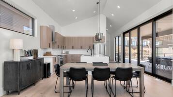 A modern kitchen with a central island, black chairs, and a dining table.