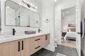A modern bathroom with a large mirror, vanity, and a shower area. - Ski & Lake Retreat | Golf Sim + Sauna + Firepit (Daniel)