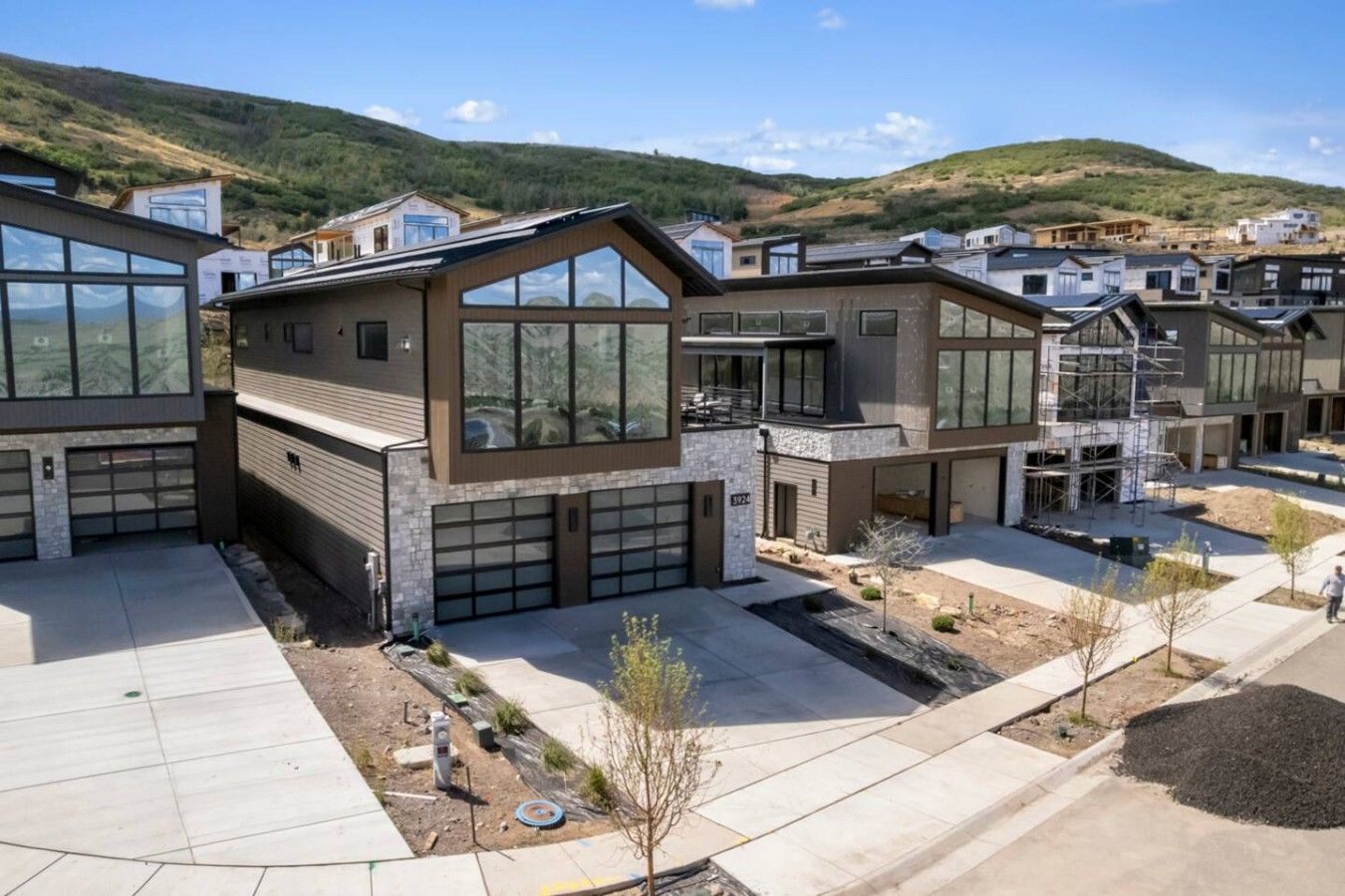 A residential area with modern houses featuring large windows, garage doors, and a landscaped front yard.