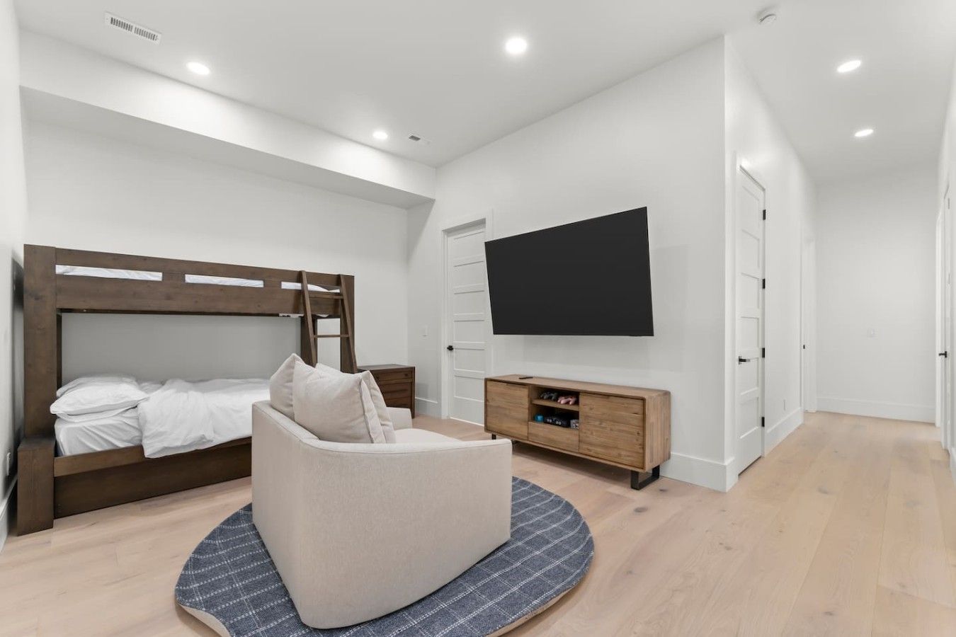 A bedroom with a bunk bed, a sofa, a TV, and a wooden cabinet.