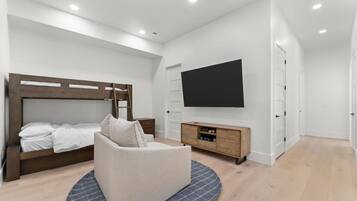 A bedroom with a bunk bed, a sofa, a TV, and a wooden cabinet.