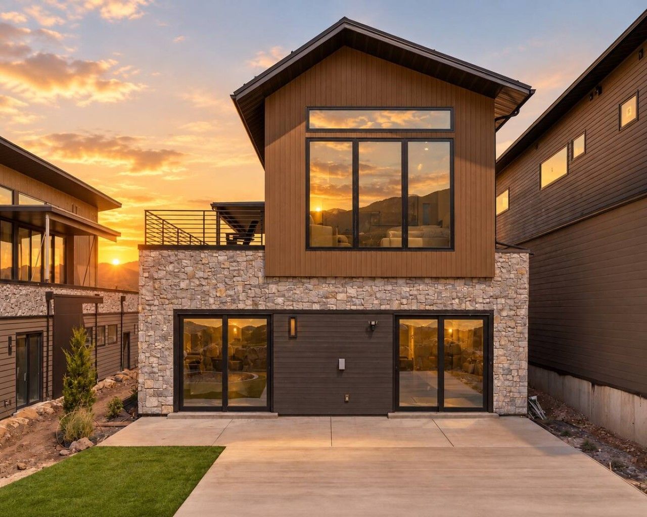 A modern two-story house with a stone facade, large windows, and a garage.