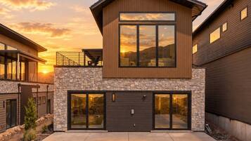 A modern two-story house with a stone facade, large windows, and a garage.