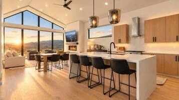 A modern kitchen with a large island, bar stools, and a view of the mountains.
