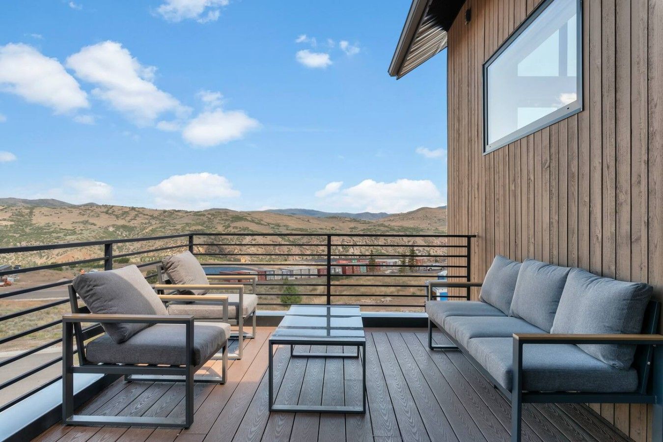 A deck with outdoor furniture, a view of the landscape, and a wooden building.