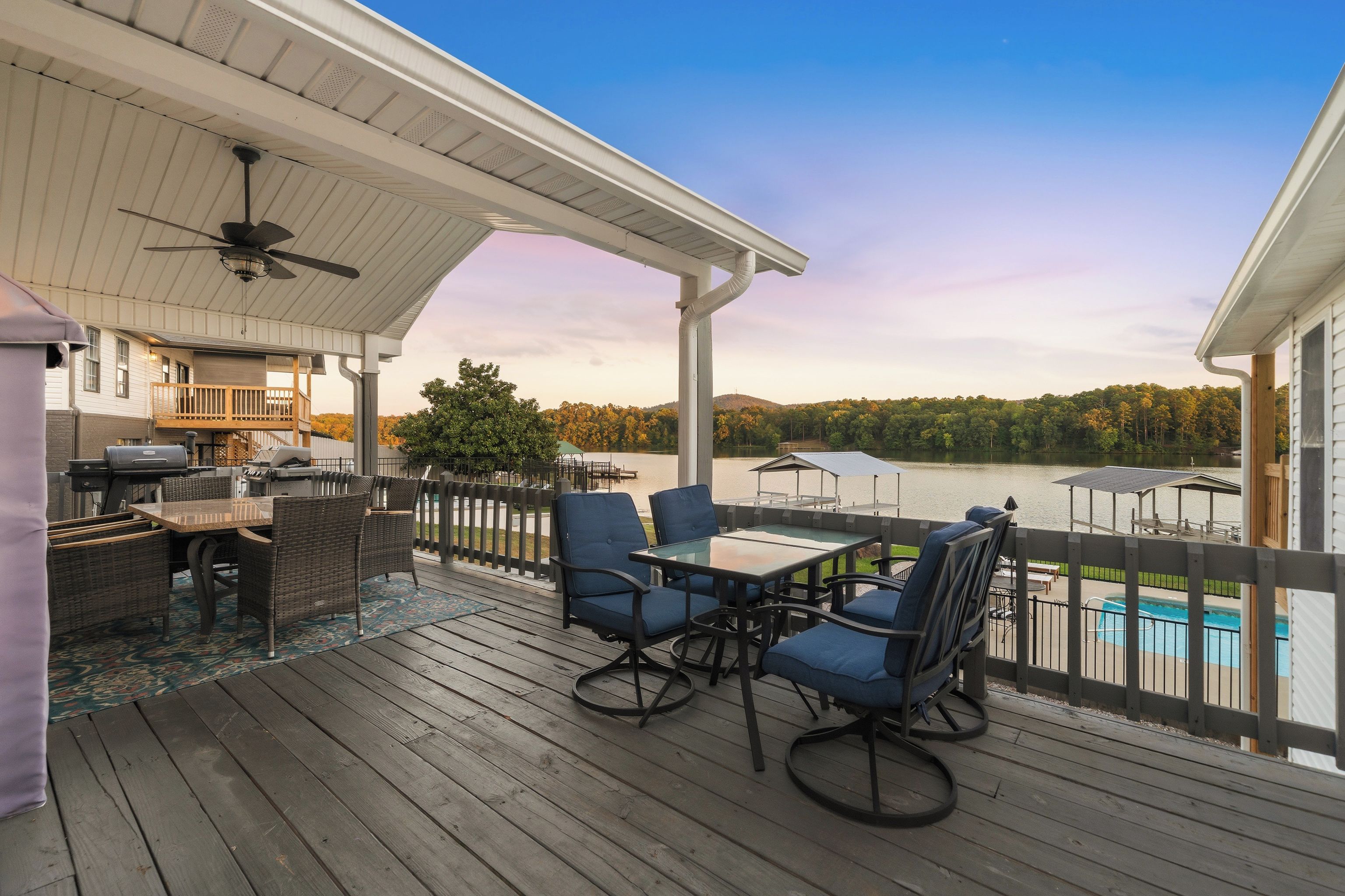 Una terraza techada al aire libre con zona de comedor, parrilla y vista al lago.
