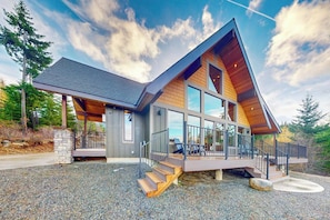 A modern house with a sloped roof, large windows, and a deck. - 5 BR modern mountain home with mountain views (Cle Elum)