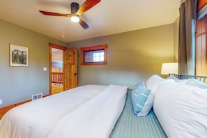 A bedroom with two beds, a ceiling fan, a window, and a door. - 5 BR modern mountain home with mountain views (Cle Elum)