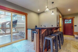 A modern kitchen with a bar area, large windows, and a view of the outdoors. - 5 BR modern mountain home with mountain views (Cle Elum)