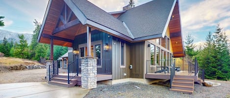 A modern two-story building with a sloped roof, large windows, and a stone foundation.