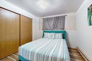 Ein Schlafzimmer mit einem Bett, einem fensterbelaubten Fenster, einem Holzschrank und einem Bild an der Wand.