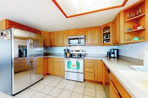 A kitchen with wooden cabinets, a stainless steel refrigerator, a microwave, and a stove.