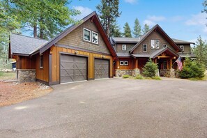 A two-story house with a garage, stone foundation, and an American flag. - 4 BR home with private hot tub and gas fire pit (Cle Elum)