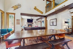 A spacious living area with a large wooden dining table, comfortable seating, a fireplace, and a loft with a balcony. - 4 BR home with private hot tub and gas fire pit (Cle Elum)