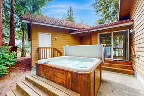 Een houten chalet met een hottub, houten traptreden en een deur.