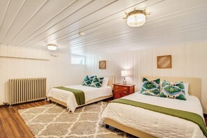 Ein Schlafzimmer mit zwei Betten, einem Heizkörper, einem Holzboden und einer Decke mit Paneelen.